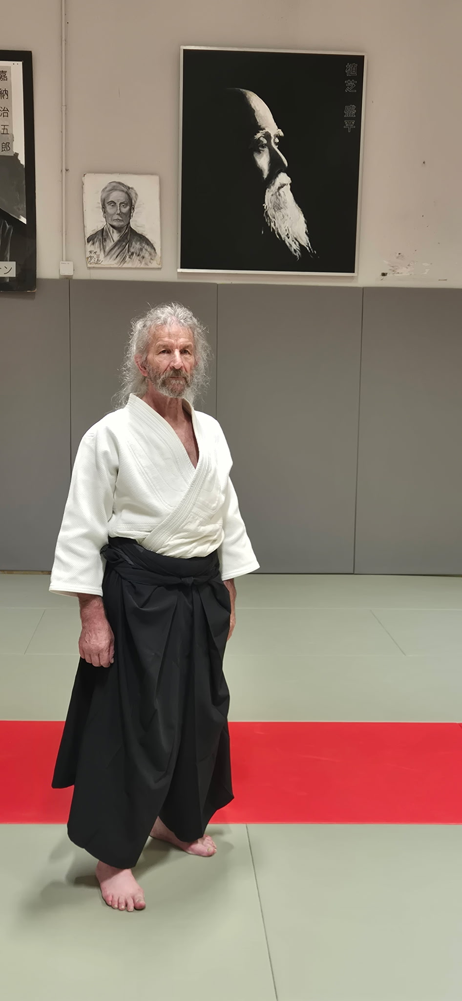 Maurice Dubreuil en tenue, au katana, sous le portrait d'O-Sensei Ueshiba